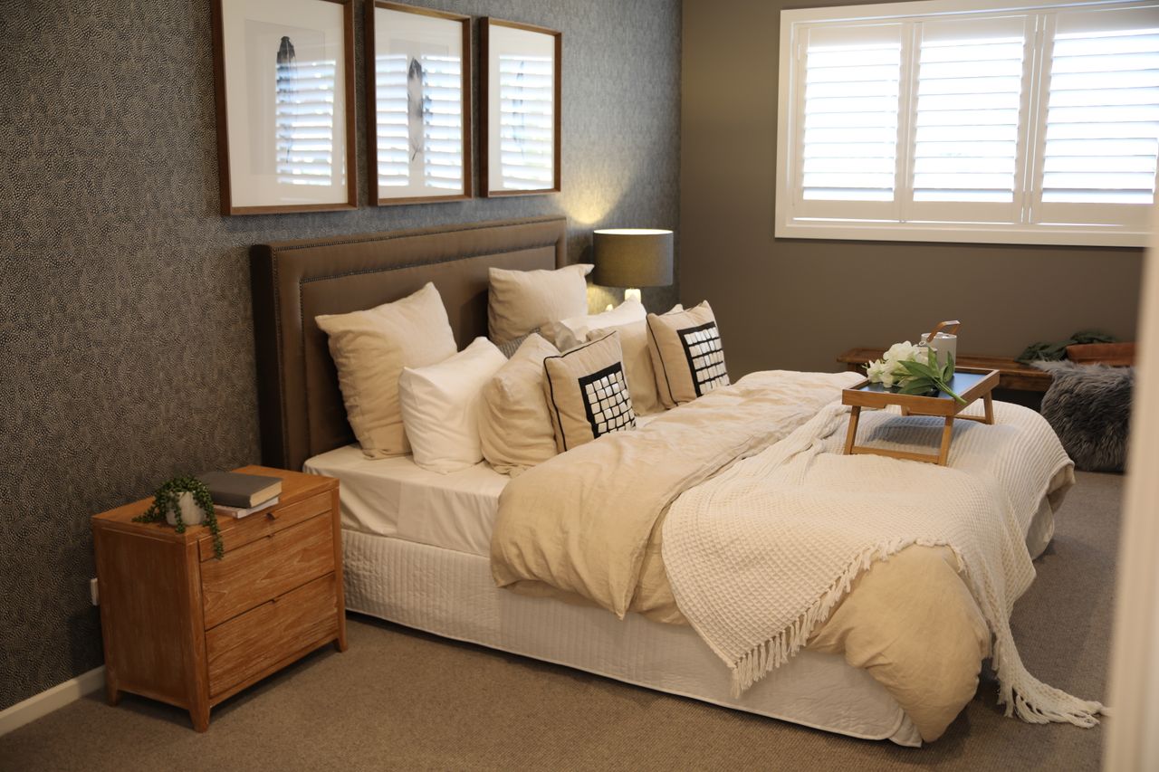 Contact Warm and inviting modern bedroom with a neatly arranged bed and stylish decor.
