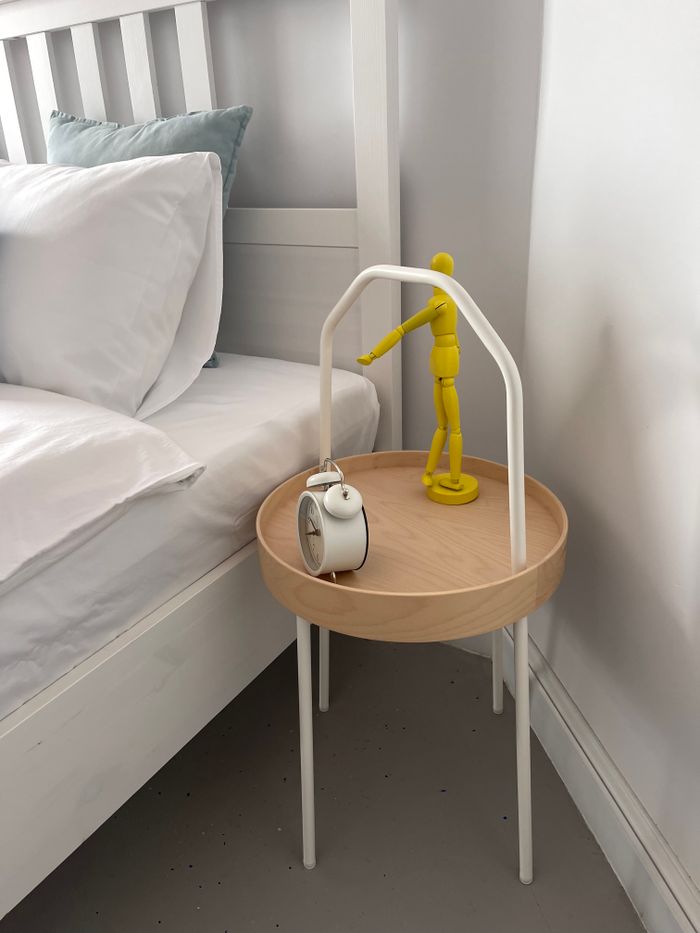 Stylish minimalist bedroom featuring a wooden side table with alarm clock and decor.